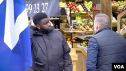 City Councilor Laurent Salles (R) talks to a Suresnes resident who says he's fed up with the political system. Salles counters critics who claim the National Front is racist. (L. Bryant/VOA)