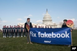 Avaaz campaigners hold a banner in front of 100 cardboard cutouts of Facebook CEO Mark Zuckerberg outside the U.S. Capitol in Washington, April 10, 2018, ahead of his Senate testimony. Avaaz, an advocacy group, is calling attention to hundreds of millions of fake accounts still spreading disinformation on Facebook and is calling for the social media giant to submit to an independent audit.