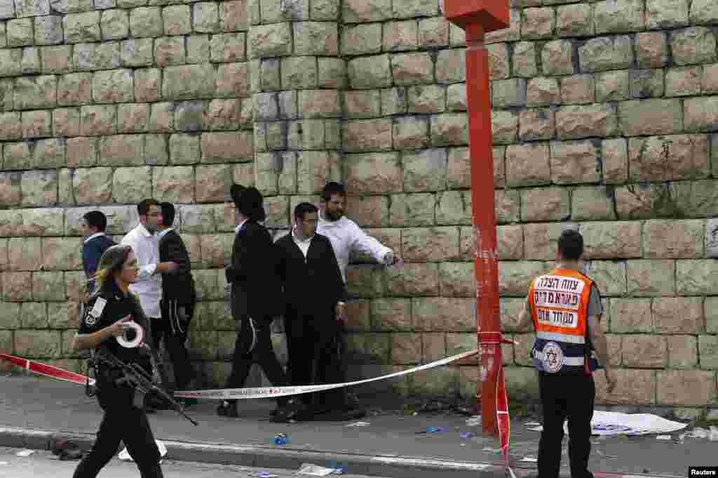 Passers-by stand at the scene of an attack in Jerusalem November 5, 2014. A motorist rammed into pedestrians on a crowded Jerusalem street and then got out of his vehicle to attack people with a metal bar on Wednesday in what Israeli police, who shot him 