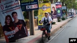 A woman rides a bicycle past electoral posters in Bangkok on March 17, 2019, ahead of the March 24 general election. 
