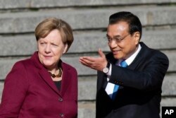 Chinese Premier Li Keqiang, right, shows the way for German Chancellor Angela Merkel during a welcome ceremony held outside the Great Hall of the People in Beijing, China, Oct. 29, 2015.