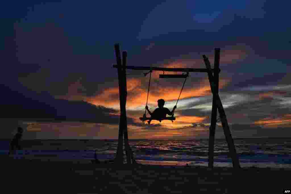 A child plays on a swing as the sun sets at Lhoknga beach in Aceh province, Indonesia.