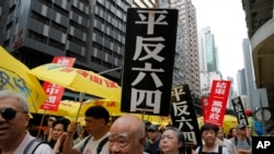 Pengunjuk rasa pro-demokrasi membawa plakat bertuliskan China bertuliskan "Vindicate 4 June" dan "End to one-party Dictatorship" saat demonstrasi di Hong Kong, Minggu, 26 Mei 2019. (Foto: AP)