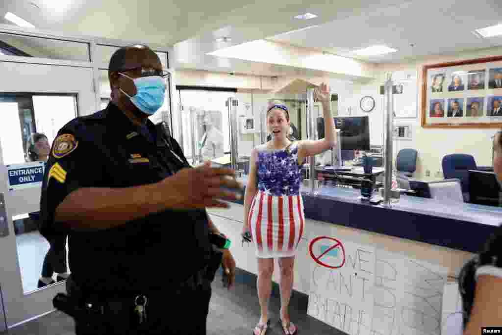 A parent and a member of the &#39;Community Patriots&#39; confront a police officer while protesting against wearing masks in schools at the Pinellas County Schools Administration Building in Largo, Florida, Aug. 9, 2021.