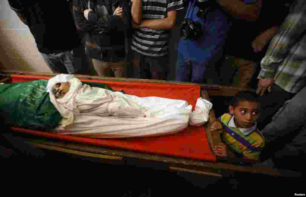 A Palestinian boy stands next to the bodies of the wife of Hamas&#39;s military leader, Mohammed Deif, and his infant son Ali, whom medics said were killed in Israeli air strikes, during their funeral, in the northern Gaza Strip, Aug. 20, 2014.