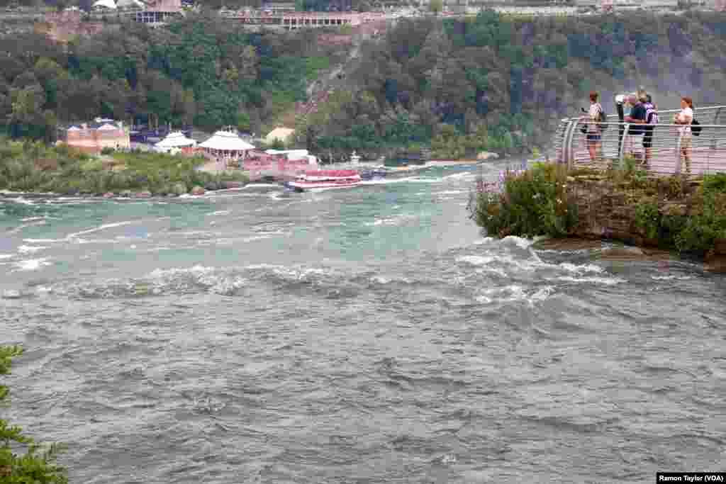 Tourists stand between the Bridal Veil and American Falls on Luna Island, Niagara Falls, New York. (R. Taylor/VOA)