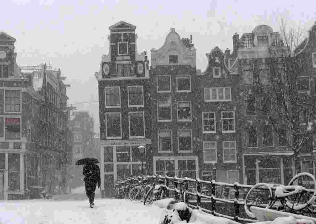 A man crosses a bridge in heavy snow in Amsterdam, Netherlands, February 3, 2012. (AP)