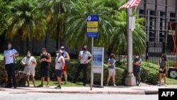 People wait for their testing at a "walk-in" and "drive-through" coronavirus testing site in Miami Beach, Florida on June 24, 2020. 