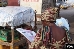 A woman reads the newspaper in Westfield, Banjul, Gambia, June 7, 2017. (S.Christensen/VOA)