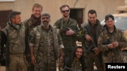 Syrian Democratic Forces (SDF) fighters pose with foreign volunteer fighters inside Tabqa military airport after taking control of it from Islamic State fighters, west of Raqqa city, Syria April 9, 2017. 