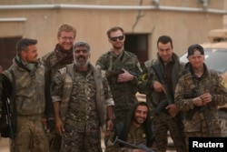 Syrian Democratic Forces (SDF) fighters pose with foreign volunteer fighters inside Tabqa military airport after taking control of it from Islamic State fighters, west of Raqqa city, Syria April 9, 2017.