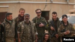 FILE - Syrian Democratic Forces (SDF) fighters pose with foreign volunteer fighters inside Tabqa military airport after taking control of it from Islamic State fighters, west of Raqqa city, Syria April 9, 2017. 