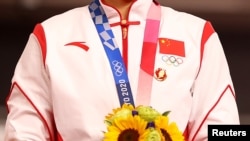 中國場地自行車女子團體賽金牌得主在東京奧運會領獎台上違反奧林匹克憲章，佩戴中共前領導人毛澤東的像章。（2021年8月2日）