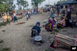 Seorang perempuan Muslim Rohingya, yang menyeberang dari Myanmar ke Bangladesh, memasak di pinggir jalan dekat kamp pengungsi Mushani, Bangladesh, Sabtu, 16 September 2017.