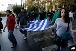 University students hold a blood-stained Greek flag from the deadly 1973 student uprising in Athens, Nov. 17, 2015. Thousands of people marched to commemorate a student uprising that was crushed by the country’s military regime in 1973.