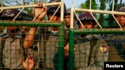 Police stand guard in front of a court, after the arrival of student protesters, in Letpadan March 11, 2015.