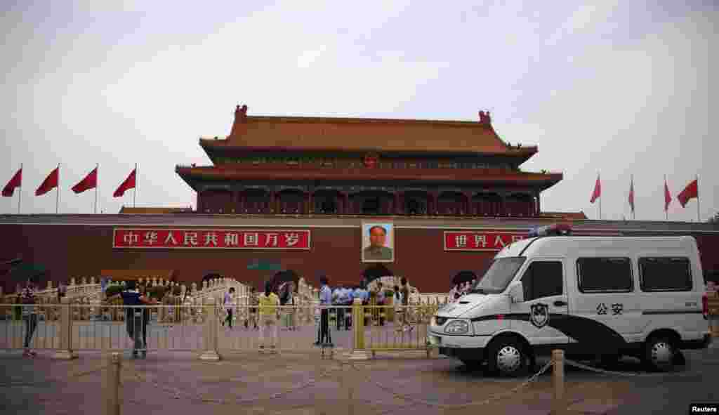 A police car is seen in front of a giant portrait of China's late Chairman Mao Zedong in Tiananmen Square in Beijing, June 4, 2014. 