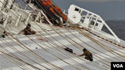 Dua orang anggota tim pertolongan Italia tengah bekerja di atas kapal Concordia (17/1). Upaya pertolongan dihentikan sementara, karena posisi kapal yang bergeser mempersulit upaya pencarian korban.