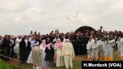 Yazidi priests release doves into the air after blessing a mass grave while the exhumation team stands by to begin their work in Kocho, Iraq, March 15, 2019. 