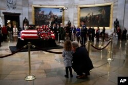 Rep. Patrick McHenry, R-N.C., kneels alongside his daughter Cecelia near the flag-draped casket of former President George H.W. Bush as he lies in state in the Capitol Rotunda in Washington, Dec. 4, 2018.