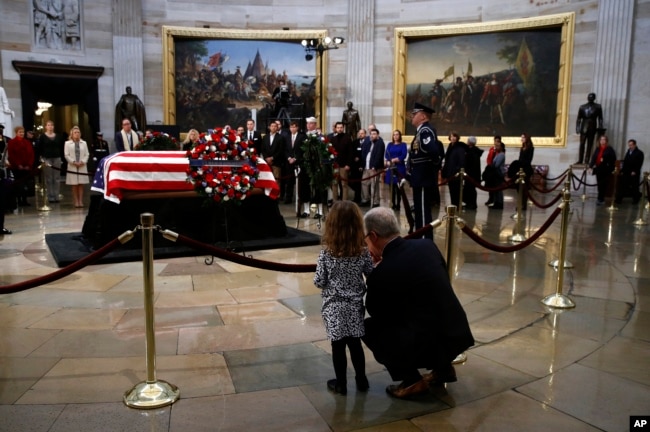 Rep. Patrick McHenry, R-N.C., kneels alongside his daughter Cecelia near the flag-draped casket of former President George H.W. Bush as he lies in state in the Capitol Rotunda in Washington, Dec. 4, 2018.