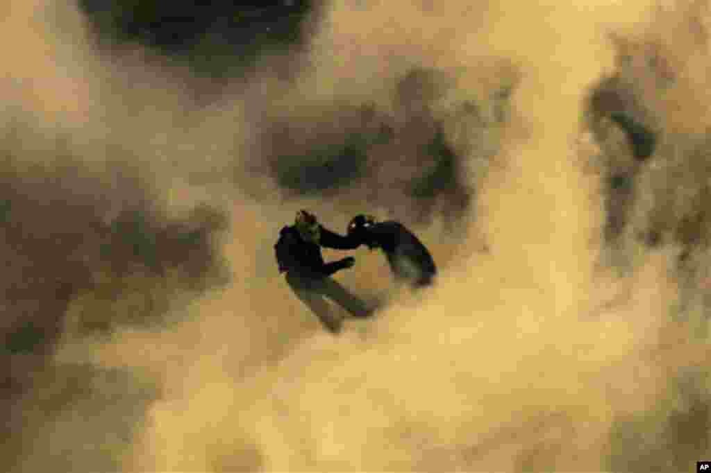 Protesters are seen through smoke from a tear gas canister throw by riot police outside the Embassy of the United States, right, in Athens, on Thursday, Nov. 17, 2011. Masked youths clashed with riot police outside Greece's parliament and the U.S. embass