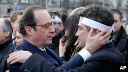 French President Francois Hollande comforts French columnist for Charlie Hebdo Patrick Pelloux in a solidarity march in the streets of Paris, Jan. 11, 2015.