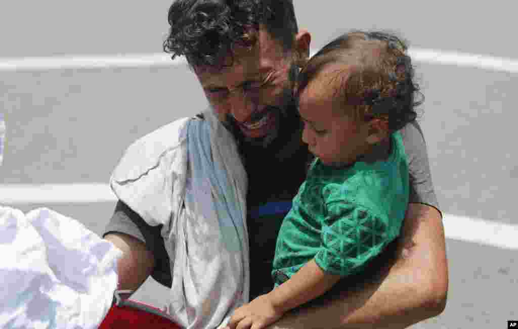 A man begs and prays not to be taken away by Mexican immigration officials as he holds his child, during a raid on a migrant caravan that had earlier crossed the Mexico-Guatemala border, near Metapa, Chiapas state, Mexico.