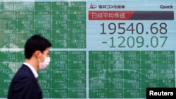 Un transeúnte usando una máscara tras el brote de coronavirus pasa frente a un cartel electrónico que muestra los índices accionarios de Asia en Tokio, Japón, el lunes, 9 de marzo de 2020.