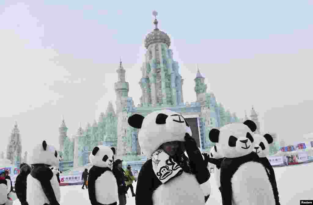Employees wearing panda costumes stand in front of ice sculptures during the Harbin International Ice and Snow World Festival in Harbin, Heilongjiang province, China.