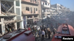 Syrian army soldiers and civilians inspect the site of two bombings in the Syrian city of Homs, in this photo provided by the state-owned Syrian Arab News Agency (SANA), Dec. 28, 2015. 