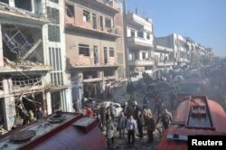 FILE - Syrian army soldiers and civilians inspect the site of two bombings in the Syrian city of Homs, in this photo provided by the state-owned Syrian Arab News Agency (SANA), Dec. 28, 2015.