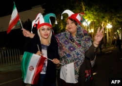 Iranian football supporters wearing the national football team's colors wave national flags outside Azadi stadium in Tehran, June 20, 2018, during a screening of the Russia 2018 World Cup Group B football match between Iran and Spain. Tehran's largest football stadium admitted thousands of women together with men for the first time since the Islamic Revolution of 1979.