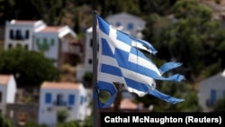 Bendera Yunani yang koyak terlihat di desa Meyisti di Pulau Kastellorizo, di bagian paling timur Yunani (4/7). (Reuters/Cathal McNaughton)