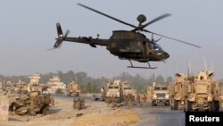 U.S. troops assess the damage to an armored vehicle of NATO-led International Security Assistance Force (ISAF) at the site of a suicide attack in Jalalabad province, Afghanistan, Aug. 24, 2014. 