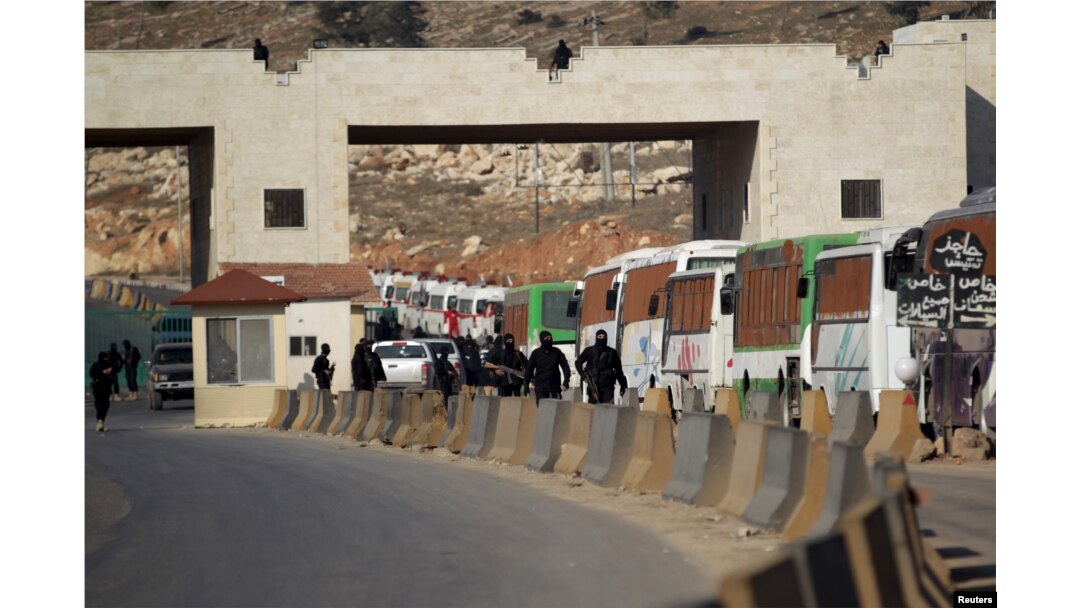 Fighters from a coalition of rebel groups called "Jaish al Fatah", also known as "Army of Fatah" (Conquest Army), secure the area while buses evacuating fighters and civilians from the two besieged Shi'ite towns of al-Foua and Kefraya in the mainly rebel-held northwestern province of Idlib, arrive at the Syrian-Turkish border crossing of Bab al-Hawa, Dec. 28, 2015.