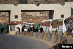 Fighters from a coalition of rebel groups called "Jaish al Fatah", also known as "Army of Fatah" (Conquest Army), secure the area while buses evacuating fighters and civilians from the two besieged Shi'ite towns of al-Foua and Kefraya in the mainly rebel-held northwestern province of Idlib, arrive at the Syrian-Turkish border crossing of Bab al-Hawa, Dec. 28, 2015.