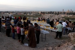 Orang-orang berkumpul untuk berbuka puasa selama bulan puasa Ramadhan, di Mosul, Irak, 15 April 2021. (Foto: REUTERS/Khalid Al-Mousily)