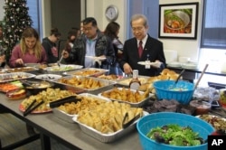 FILE - Tri Phan, right, begins the lunch line for his retirement party at Lutheran Social Services in Fargo, N.D., Dec. 15, 2017. Phan, 66, spent nearly three decades working in the agency's refugee resettlement program, helping thousands of immigrants from dozens of countries become U.S. citizens.