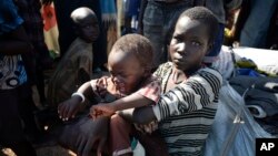 A newly-arrived displaced woman holds a child as they sit in the U.N. base in Bentiu, South Sudan, June 29, 2015. 