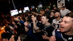 Coleman Hands, center, of Dallas, Davis Smith, second from right, of Austin, Texas, and Brian Moran, right, of Boston cheer while watching the first half of the NFL Super Bowl 52 football game between the New England Patriots and the Philadelphia Eagles in Minneapolis, Sunday, Feb. 4, 2018.
