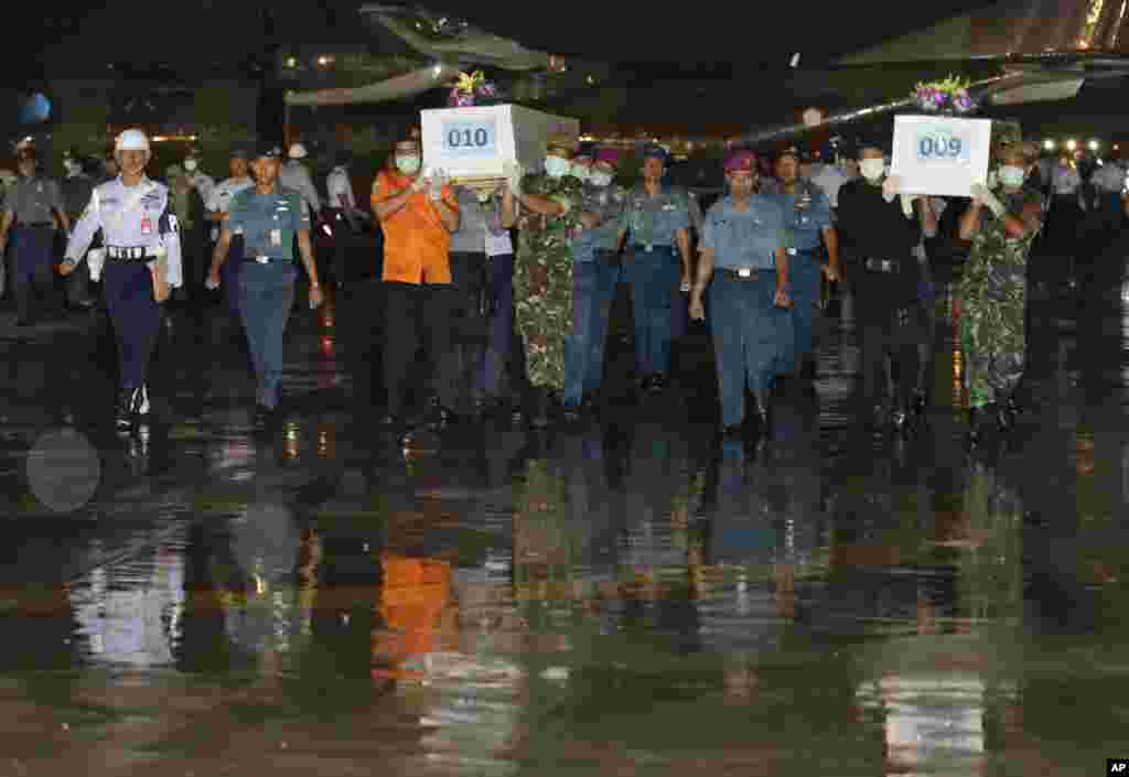 Anggota Militer Indonesia mengangkat peti jenazah korban AirAsia 8501 di Pangkalan Angkatan Udara Surabaya, Jawa Timur (2/1).