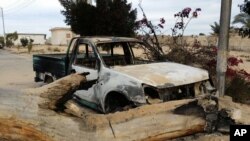 FILE - A burned truck is seen outside Al-Rawda Mosque in Bir al-Abd northern Sinai, Egypt a day after attackers killed hundreds of worshippers, on Nov. 25, 2017.