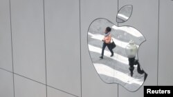 FILE - A woman is reflected in an Apple store logo in San Francisco, Aug. 21, 2017.