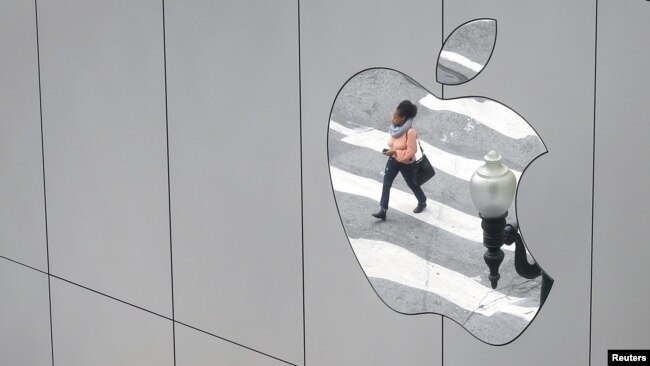 FILE - A woman is reflected in a Apple store logo in San Francisco, Aug. 21, 2017.