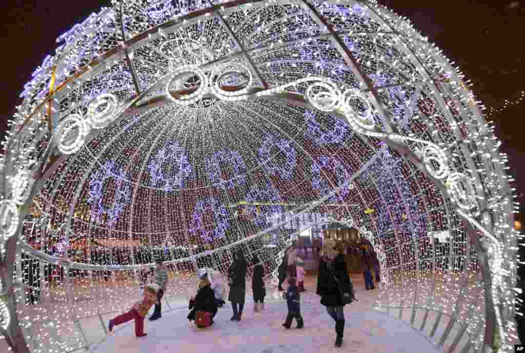 People walk inside an illuminated giant Christmas ball installed in Octyabrskaya Square and decorated to mark the upcoming Christmas and New Year celebrations in Minsk, Belarus.