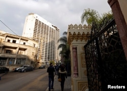 Visitors walk near the ravaged Holiday Inn building in Beirut, Lebanon, Jan. 28, 2018.