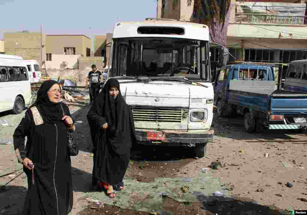 Women walk near the site of a car bomb at a bus station in Baghdad's Al-Mashtal district, Oct. 27, 2013.