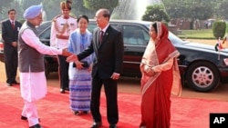 Burma's President Thein Sein (2nd R) extends his hand to Indian Prime Minister Manmohan Singh as India's President Pratibha Patil (R) and Sein's wife Khin Khin Win (in blue) watch during the ceremonial reception in New Delhi, October 14, 2011.