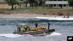 FILE - A group of Vietnamese asylum seekers are taken by barge to a jetty on Australia's Christmas Island. Australian officials said police regained control of the center after negotiating with the inmates, but added it had to use 'some force' with a group of detainees who had barricaded themselves and threatened to use weapons.